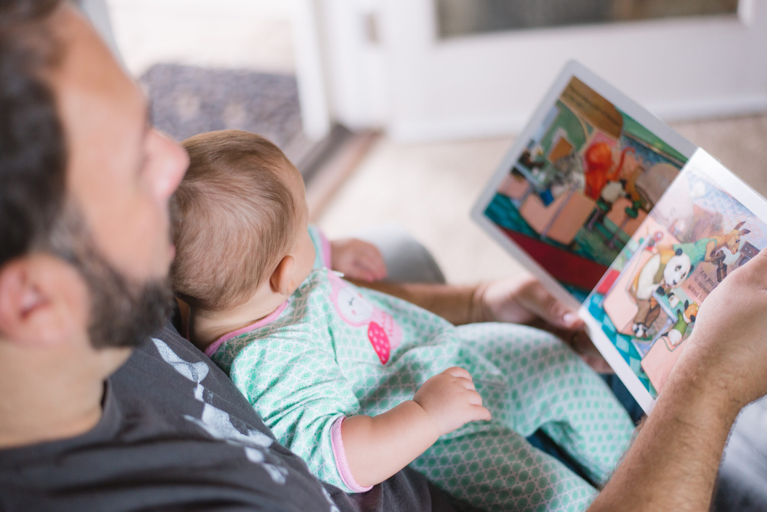 Father with infant in lap reading children's book together