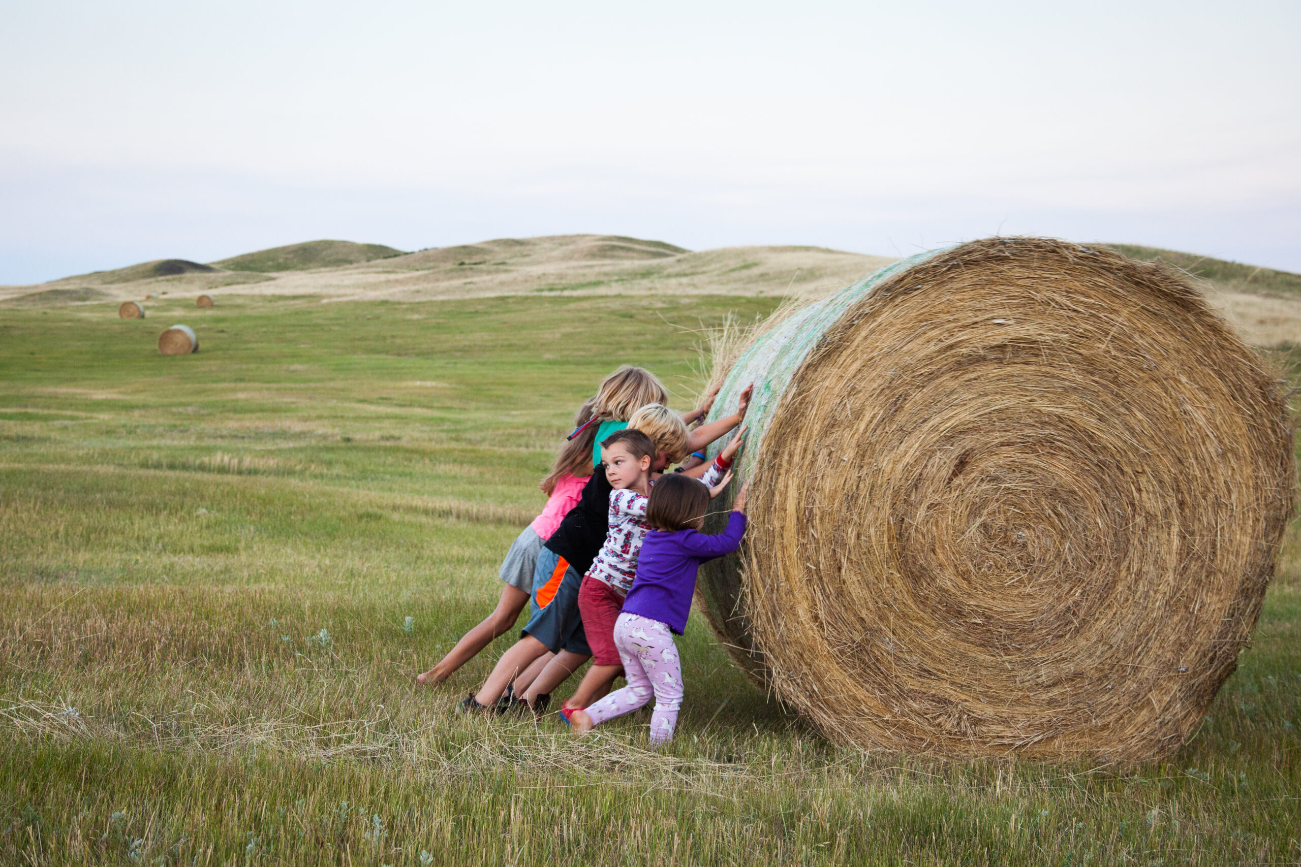 kids pushing a bale of hay