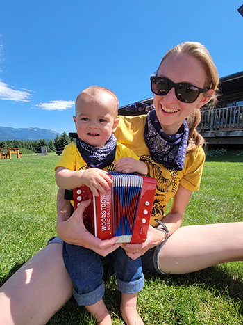 A mom holding her son and an accordion, used to describe our history and origin